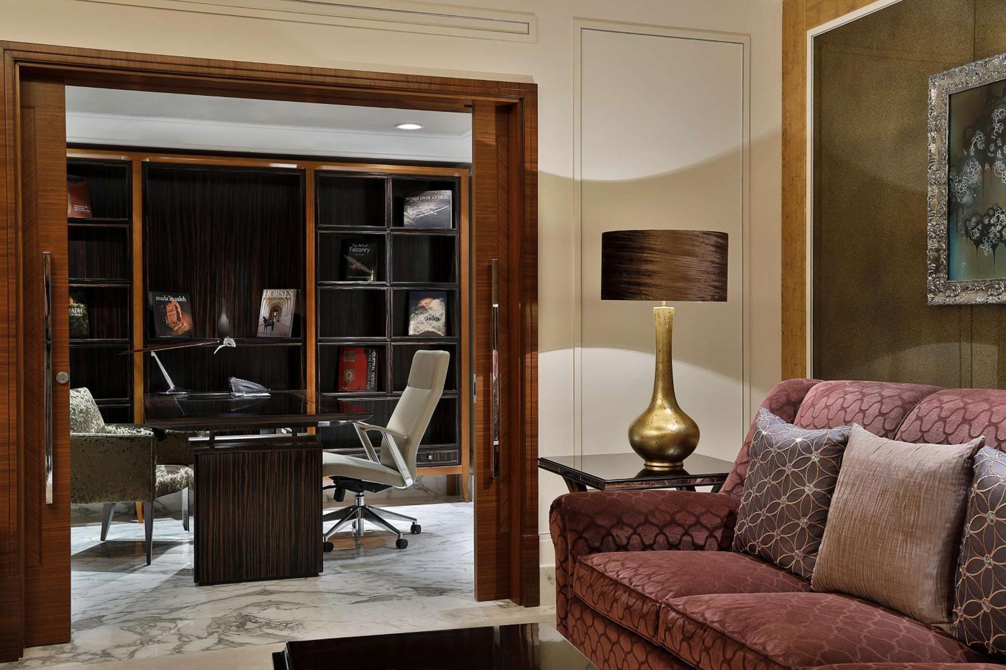 Hilton Riyadh Hotel & Residences エクステリア 写真 The photo shows a stylish and modern interior space that appears to be a home office or study. In the foreground, there is a comfortable burgundy sofa with decorative pillows. Behind the sofa, there is a doorway leading to the office area, which incl