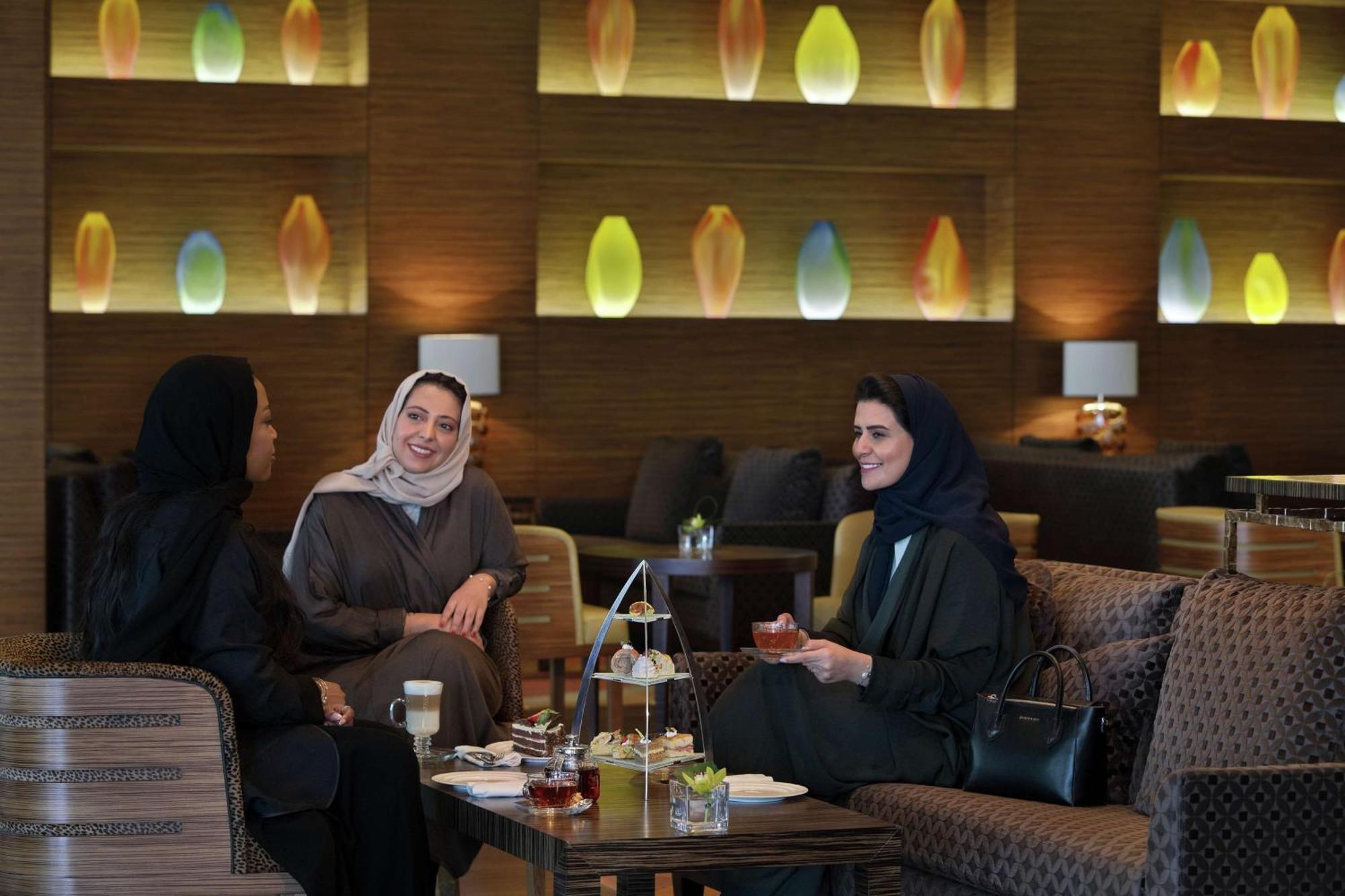Hilton Riyadh Hotel & Residences エクステリア 写真 The photo shows three women sitting together in a cozy, well-decorated lounge. They appear to be enjoying each other's company, engaged in conversation and possibly sharing tea or refreshments. The setting features soft, modern lighting with decorati