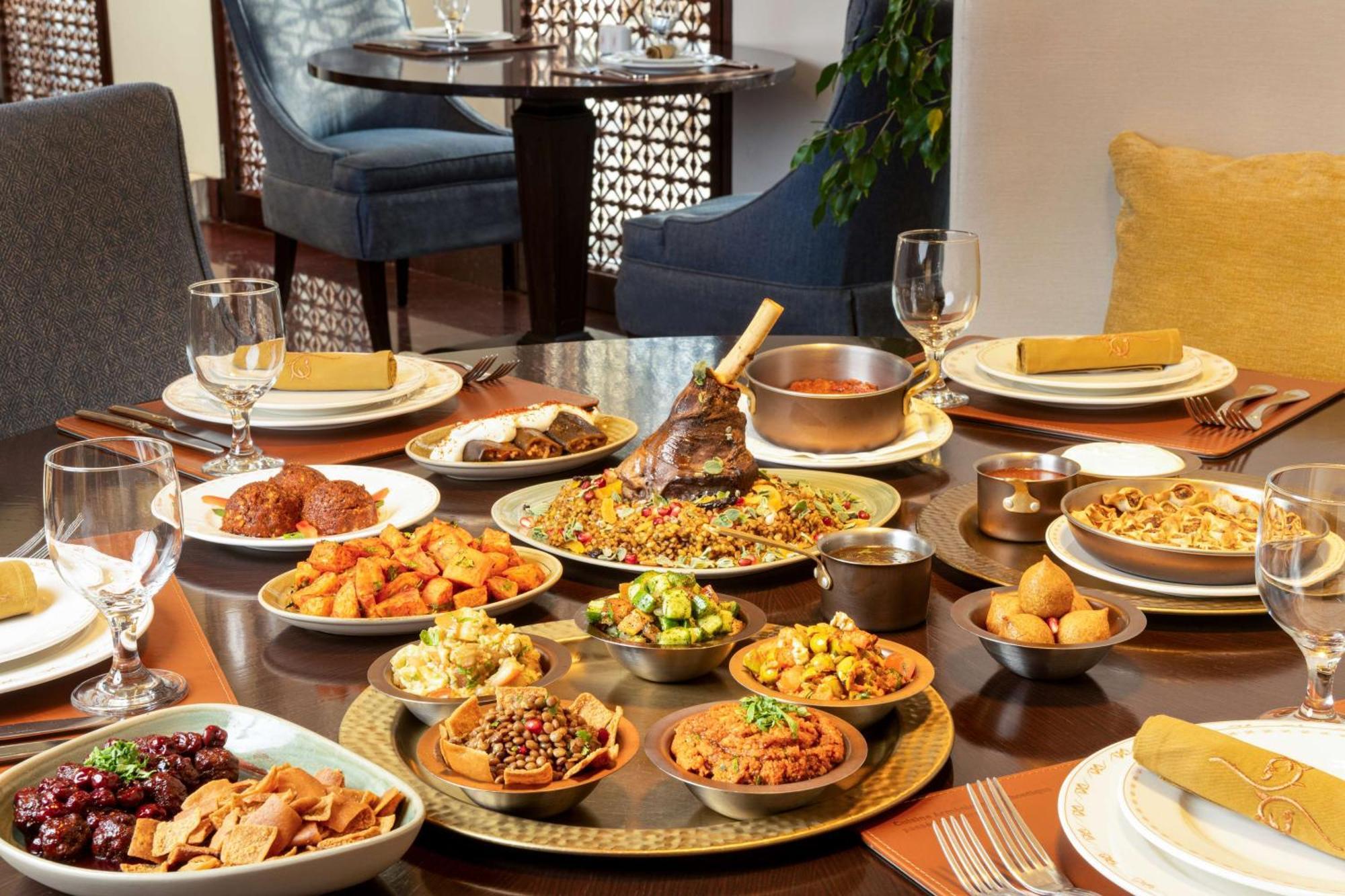 Hilton Riyadh Hotel & Residences エクステリア 写真 The photo depicts a beautifully arranged dining table featuring a variety of dishes. There are several large plates filled with different foods, including a prominent dish at the center that appears to be rice and meat, likely a type of biryani or pi