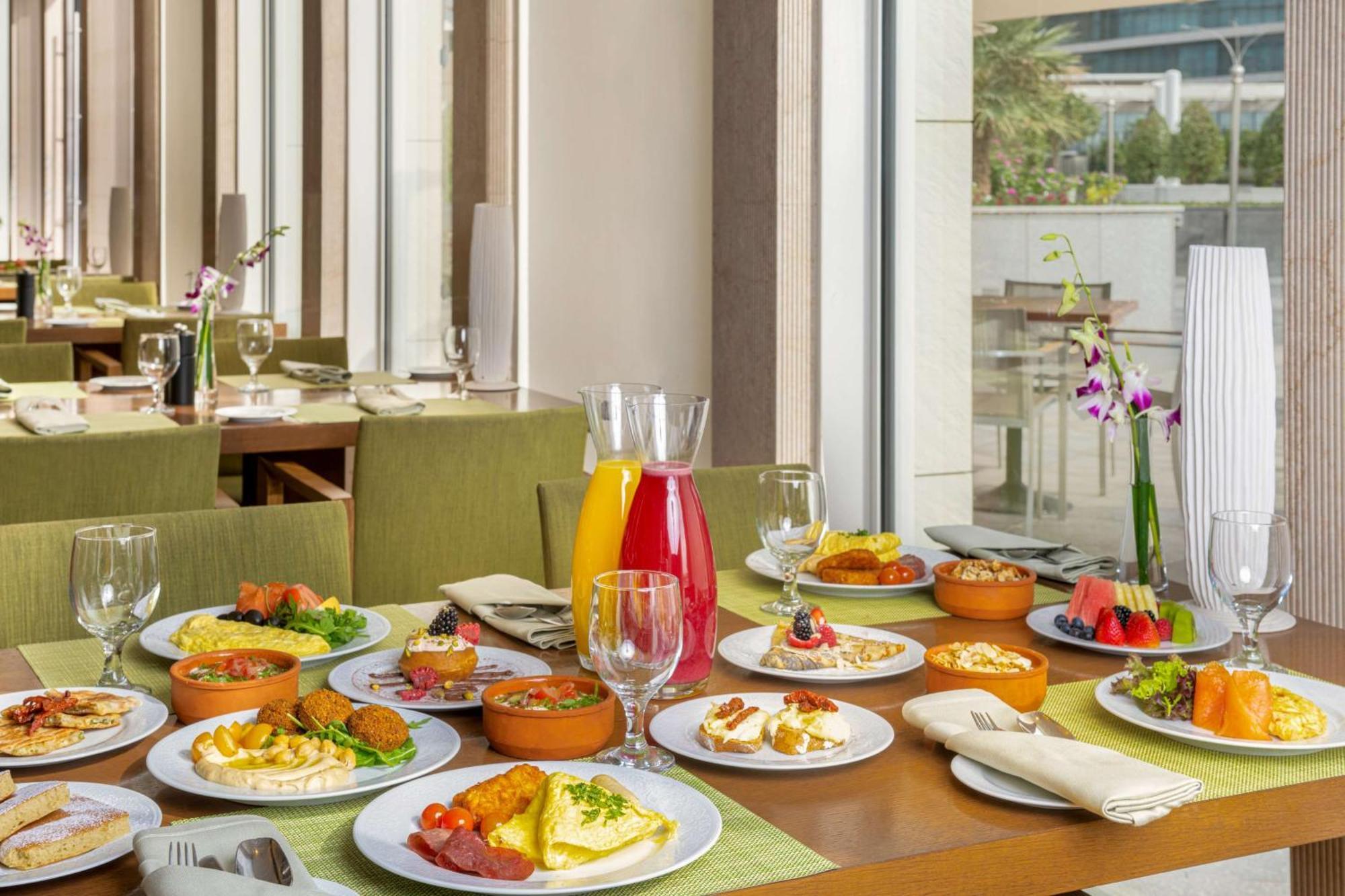Hilton Riyadh Hotel & Residences エクステリア 写真 The photo showcases a beautifully arranged dining table filled with a variety of dishes. There are multiple plates featuring an assortment of foods, including salads, appetizers, and main courses, presented in a vibrant and appetizing manner. Additio